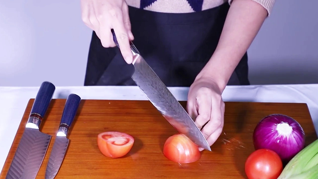 Carica il video: Video demo of elegant 8 inch Damascus steel chef knife with textured blue handle and ultra sharp patterned blade for professional kitchen cutting and food preparation
