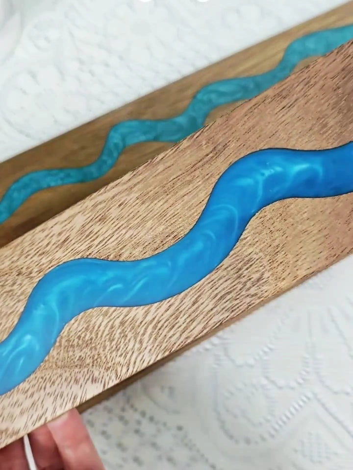 Acacia wood magnetic knife holder with blue and green resin river displaying premium kitchen knives.